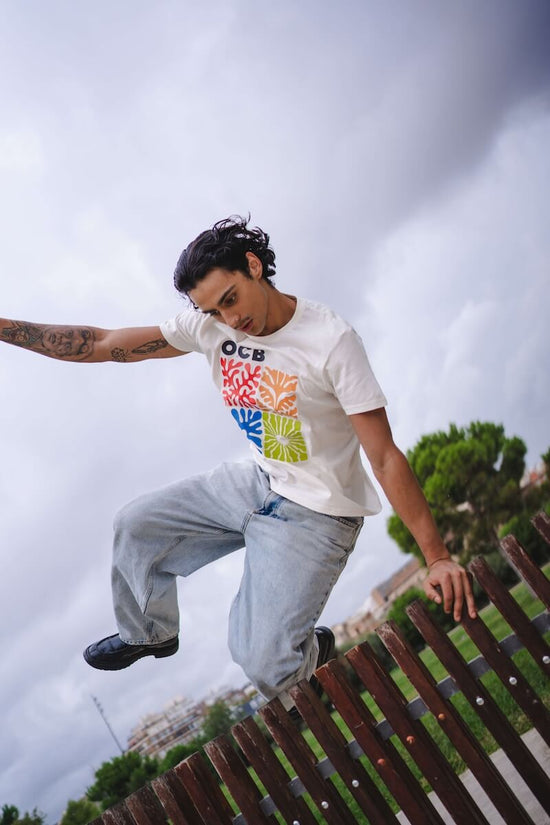 Person jumping on a wooden railing with a cloudy sky in the background