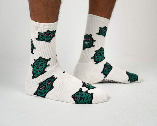 White socks with green monster patterns worn by a person on a white background